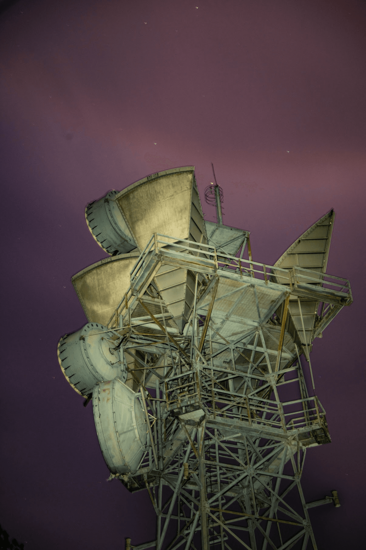 An old AT&T Long Lines antenna tower beneath a purple night sky dotted with stars, photographed by Matthew