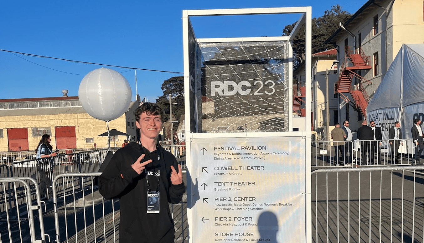 Matthew wearing an attendee badge and standing beside the RDC23 conference sign